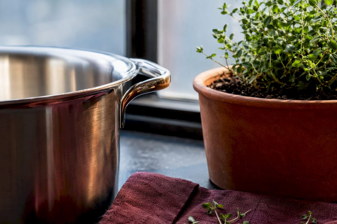 Cropped cooking pot beside herb planter