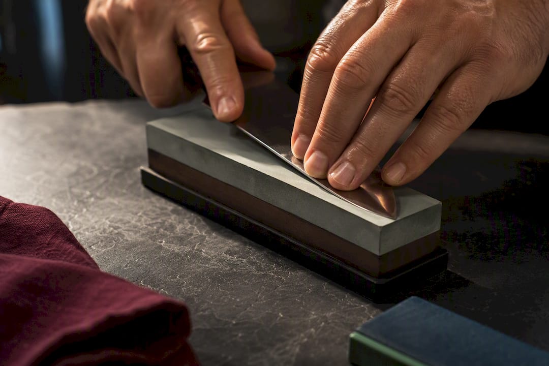 Hands sharpening knife on whetstone