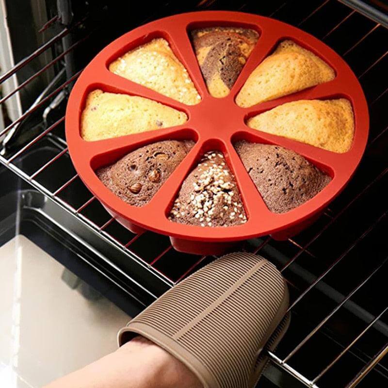 Red silicone muffin tray with baked muffins on an oven rack, held by a person wearing an oven mitt.