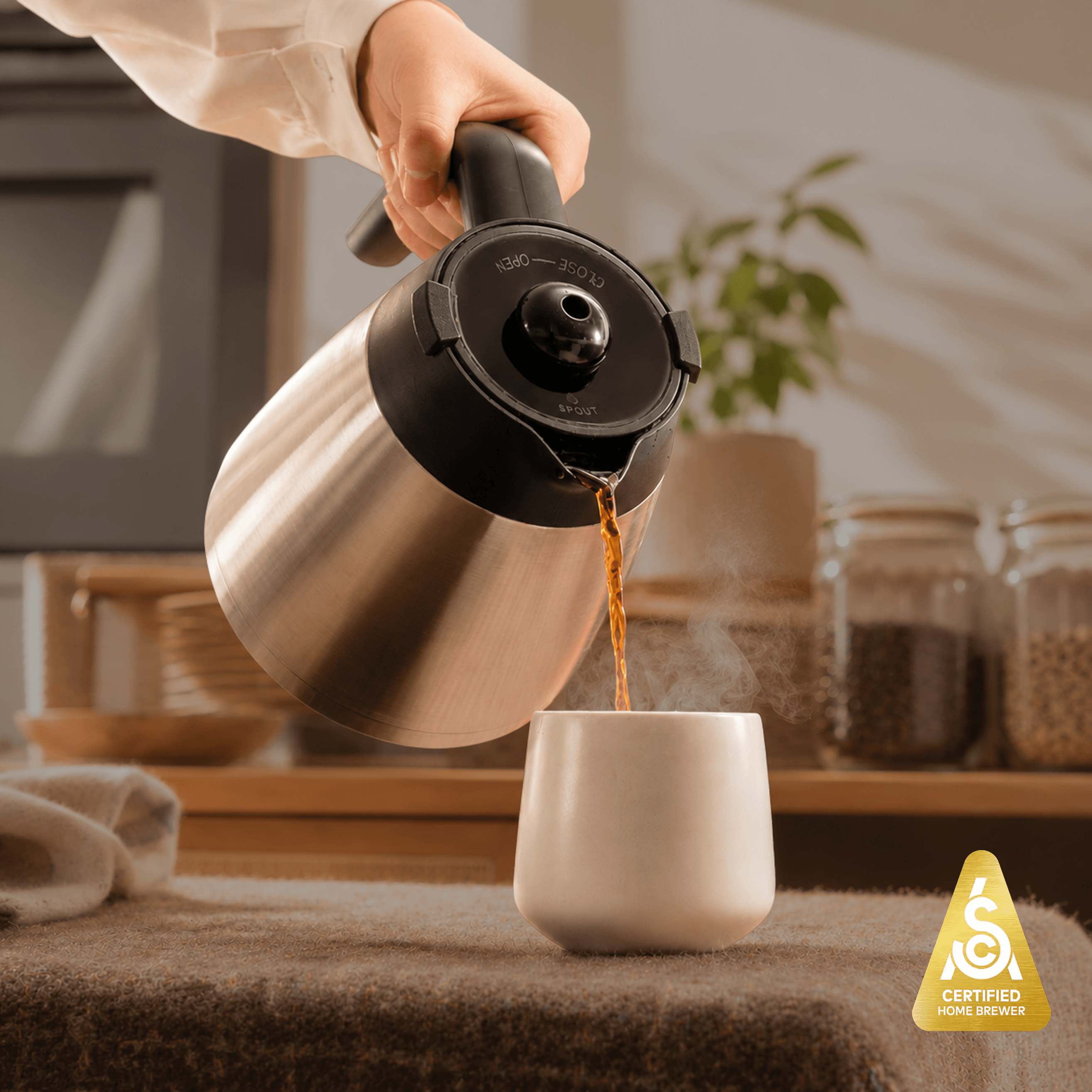 User pouring coffee from a stainless steel carafe into a cup, showcasing the 8-cup drip coffee brewer in action.