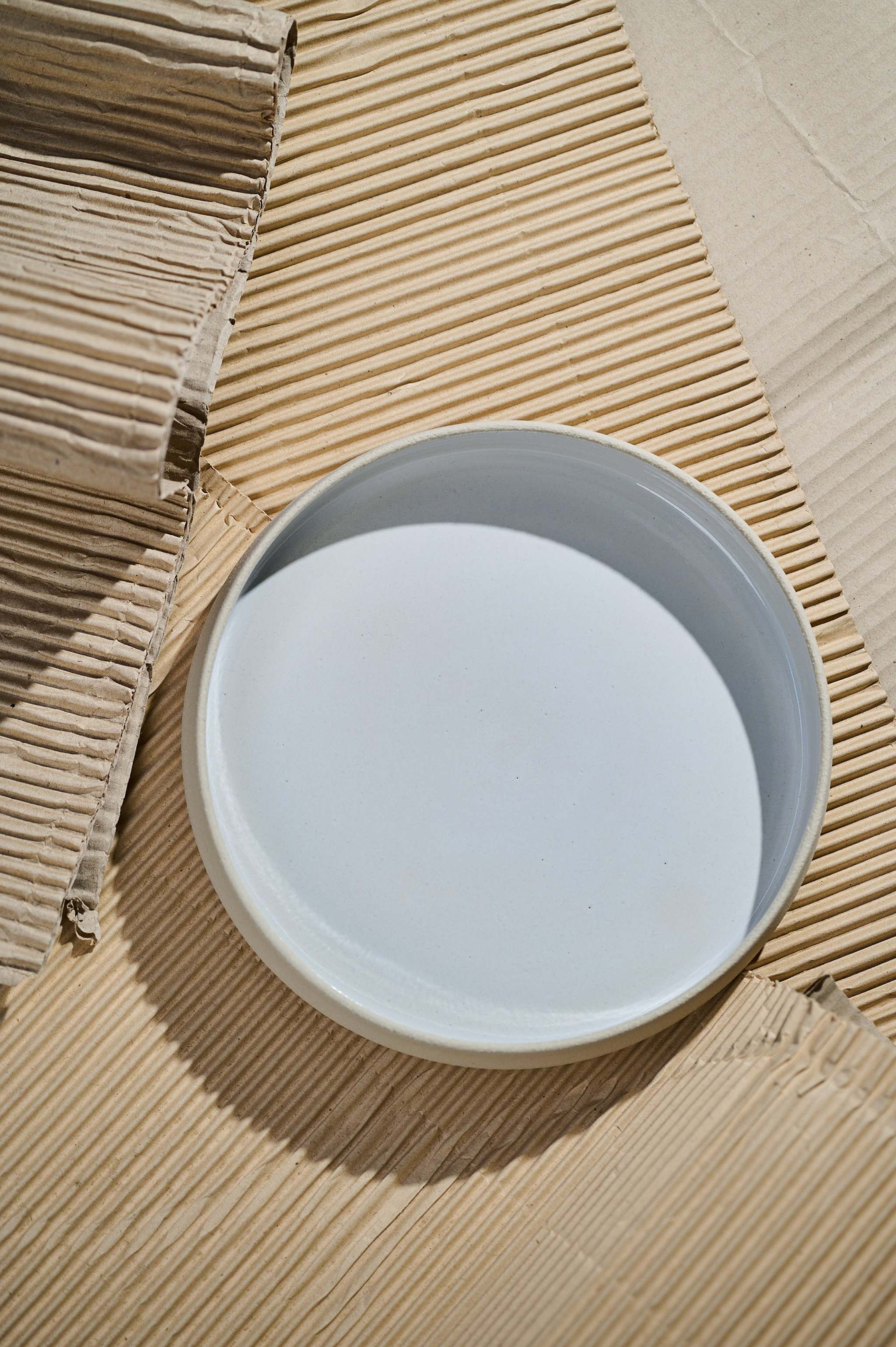 Handmade stoneware dinner plates with high sides, featuring a smooth, glossy white interior and textured exterior.