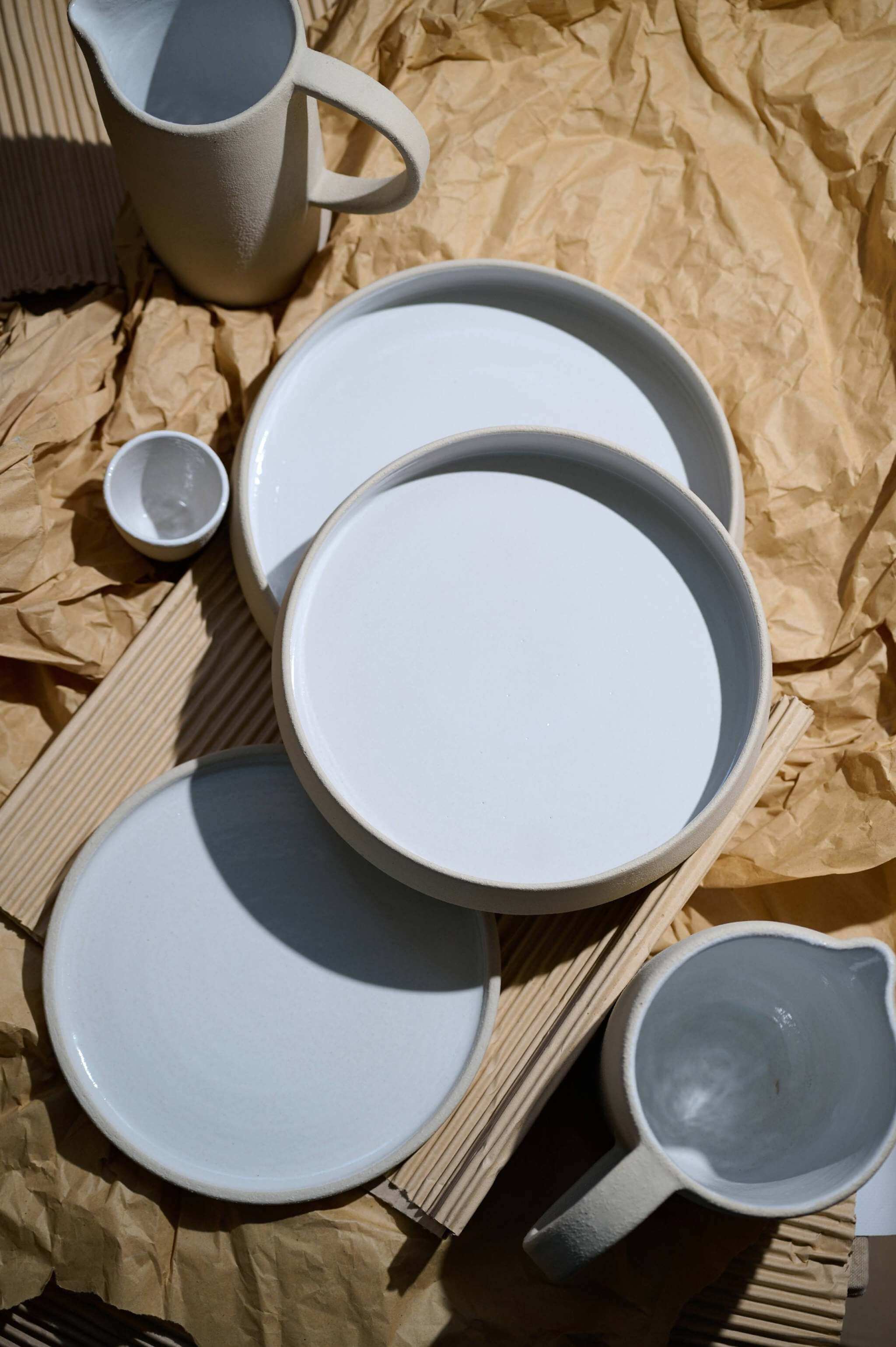 Handmade stoneware dinner plates with high sides, showcasing textured exteriors and glossy white interiors.