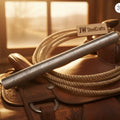 Damascus steel honing rod resting on a saddle with ropes in a warm, rustic setting.