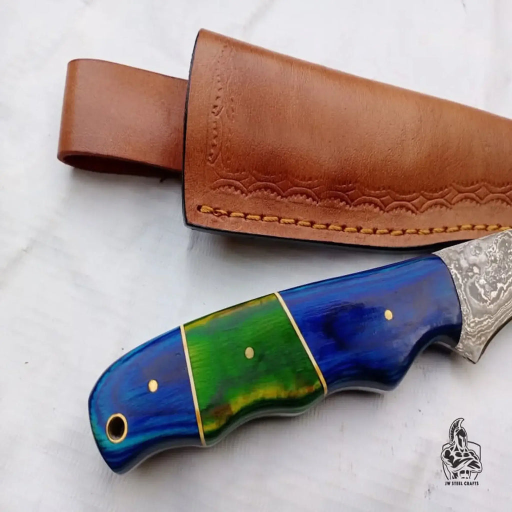 Handmade Damascus fillet knife with a colored wood handle and leather sheath, showcasing craftsmanship and design.