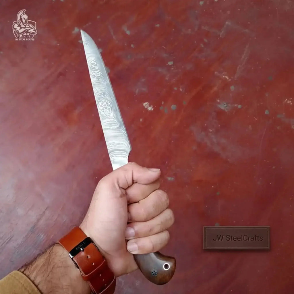 Handmade Damascus fillet knife held in hand showcasing its unique blade design and craftsmanship.