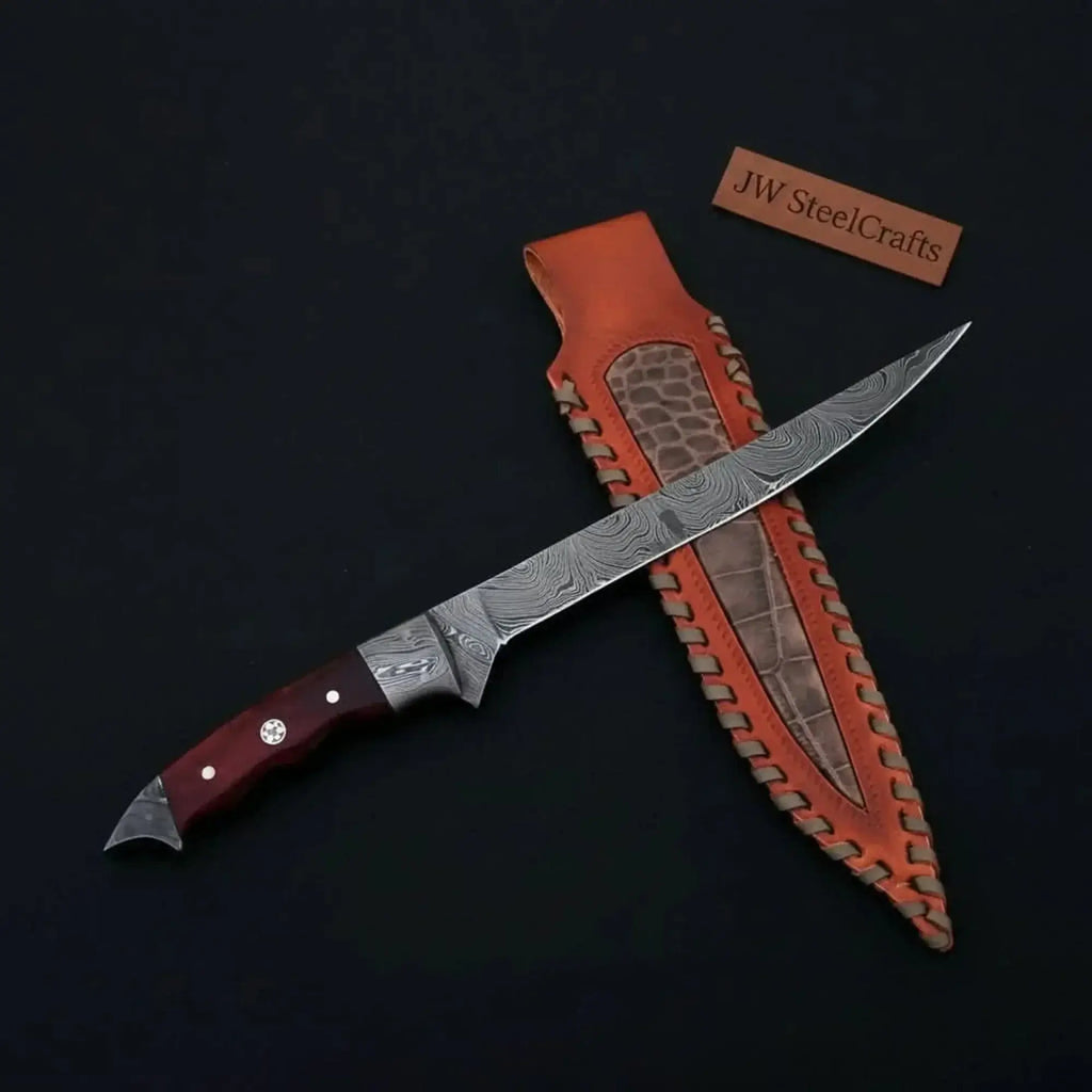 Handmade Damascus fillet knife with hardwood handle and leather sheath displayed on a dark background.