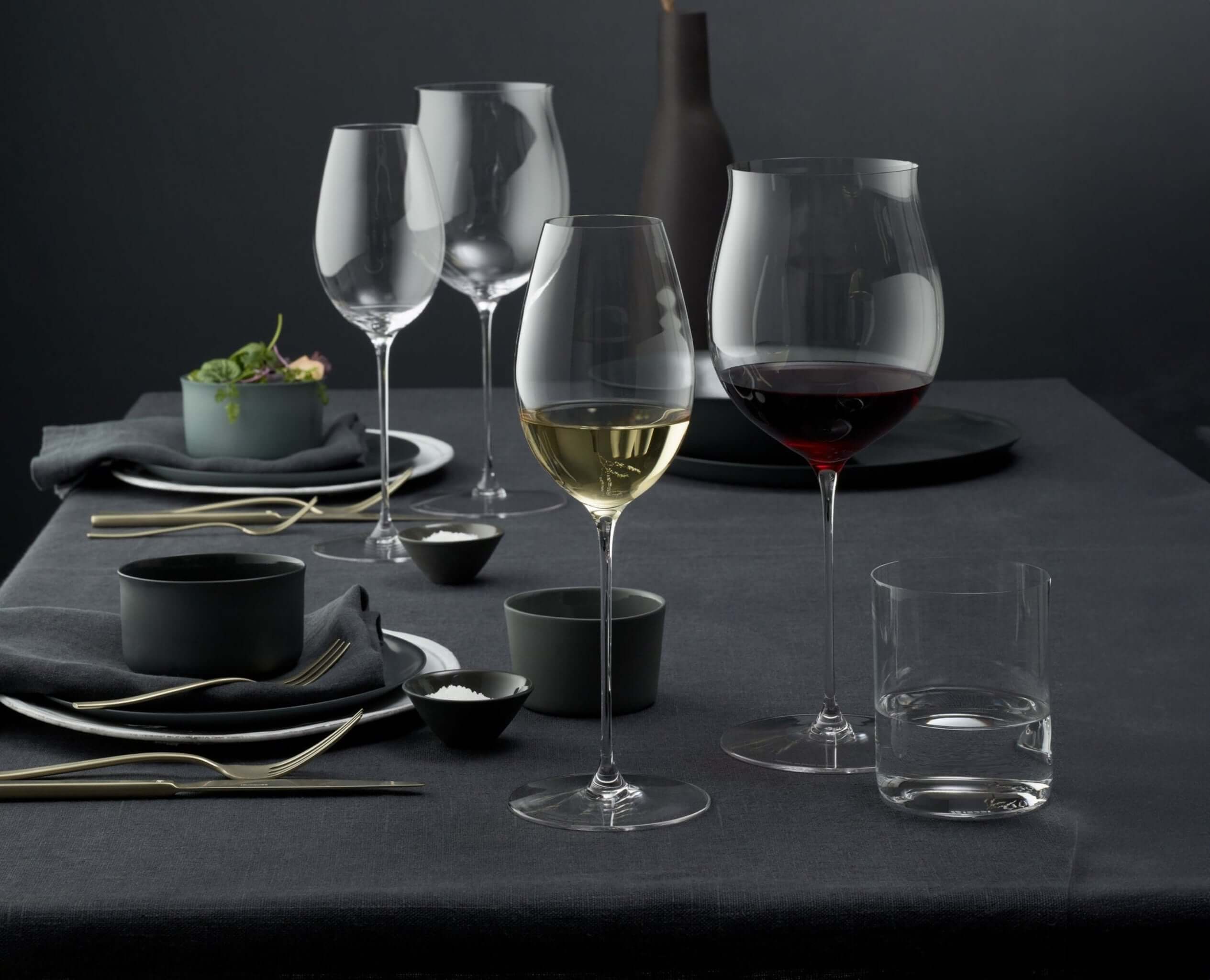 Riedel Superleggero Burgundy wine glass on an elegant dining table with wine and tableware.