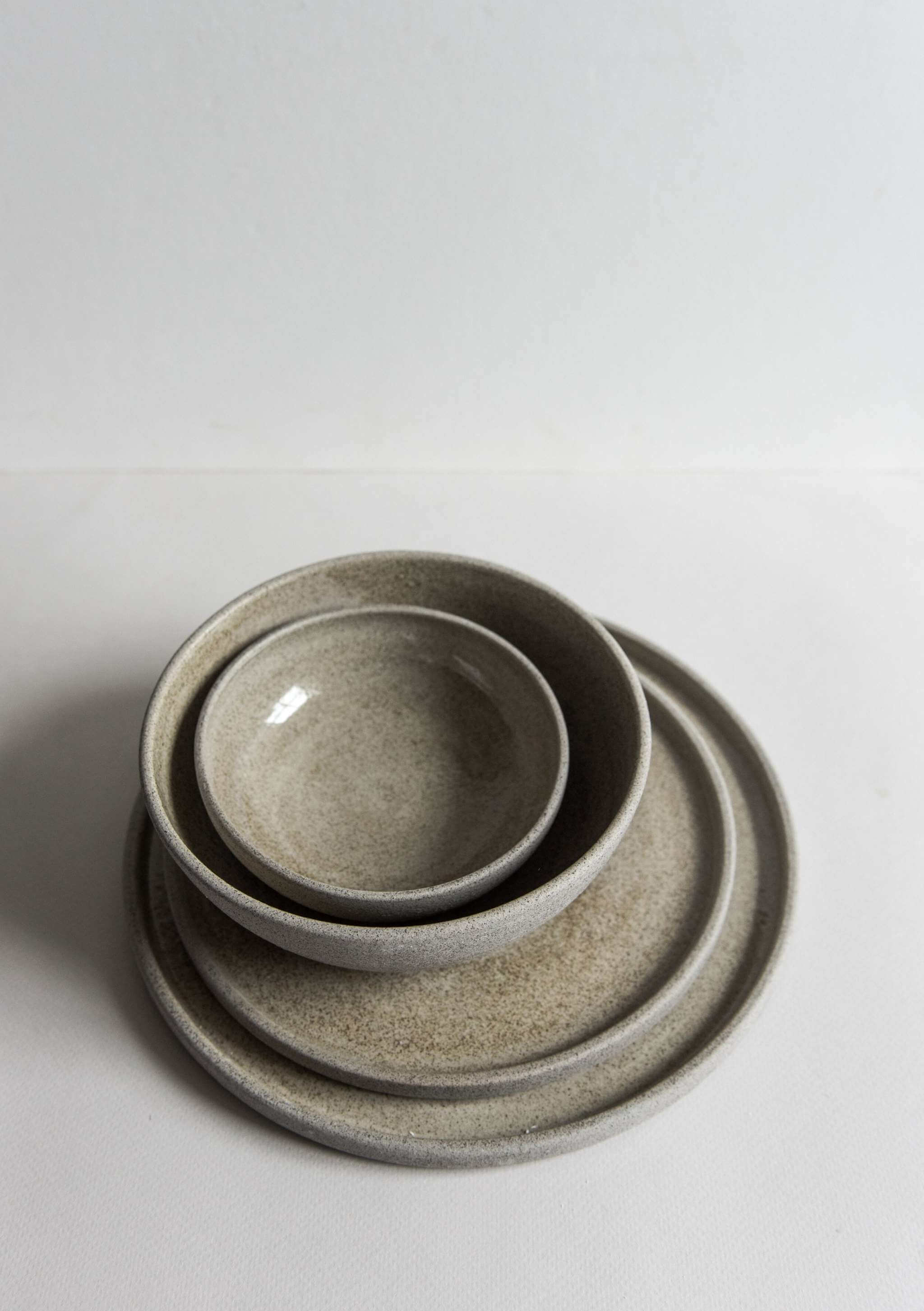 Stoneware dinner plates "Concrete" stacked with bowls showcasing rustic design and polished glaze.