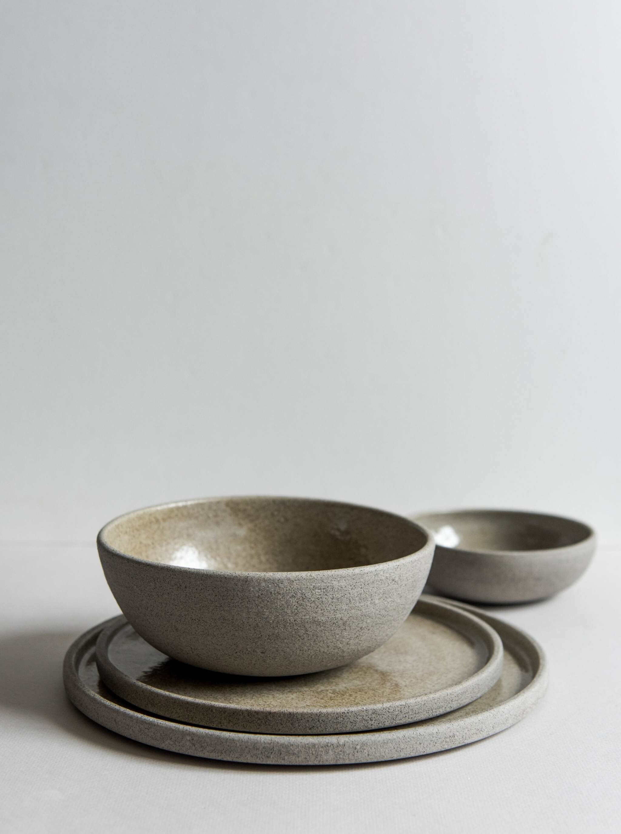 Stoneware dinner plates "Concrete" with rustic texture and glossy finish displayed together.