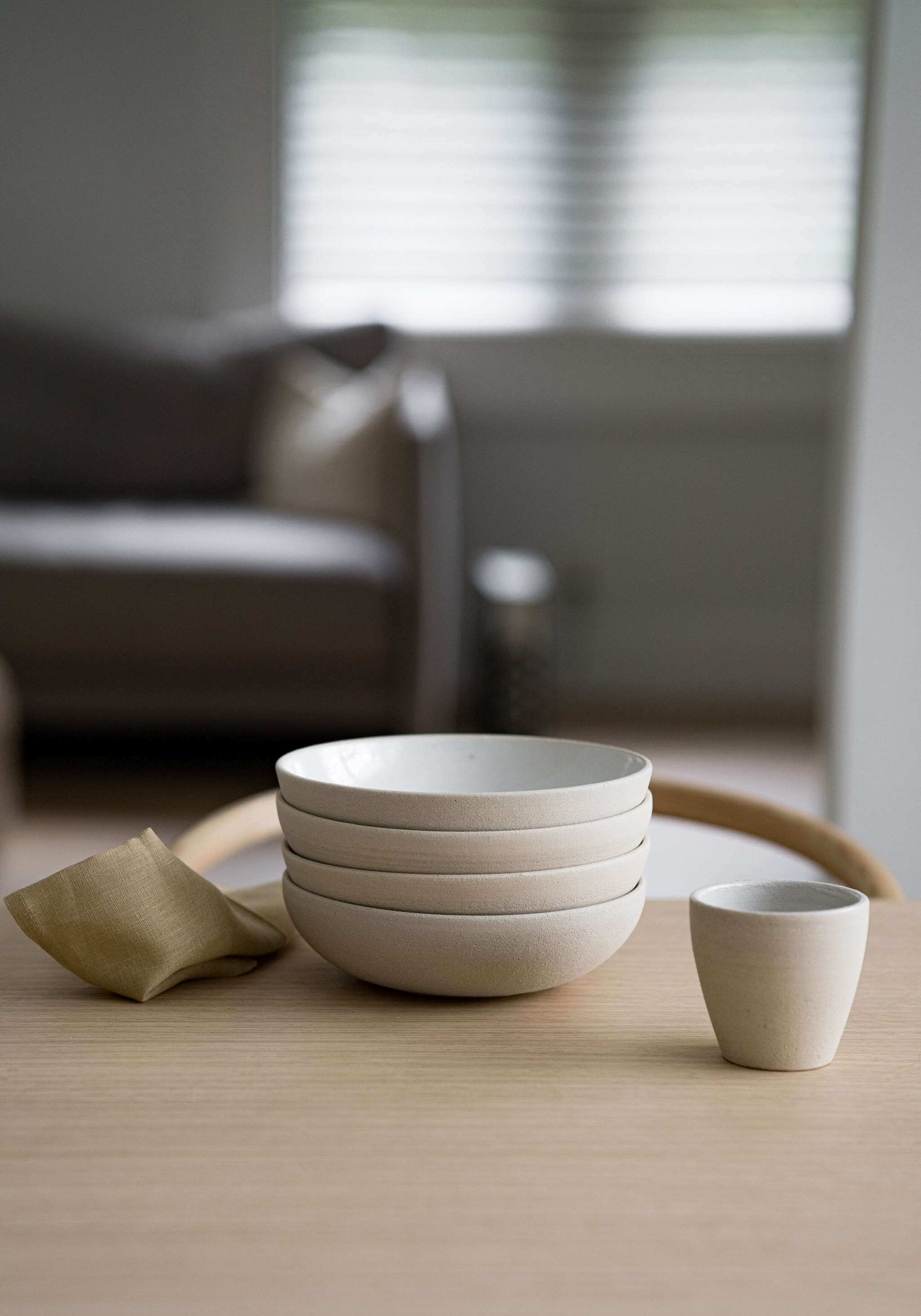 Handmade Stoneware -Coffee Cup next to stacked bowls on a wooden table.