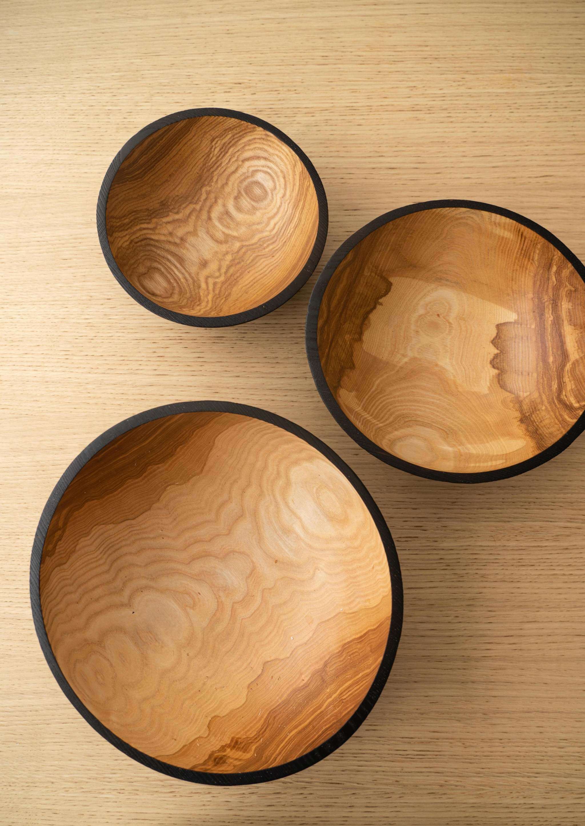 Half Charred Ashwood Nesting Bowl Set Half charred wood nesting bowl set in three sizes, showcasing natural wood patterns and black charred edges.