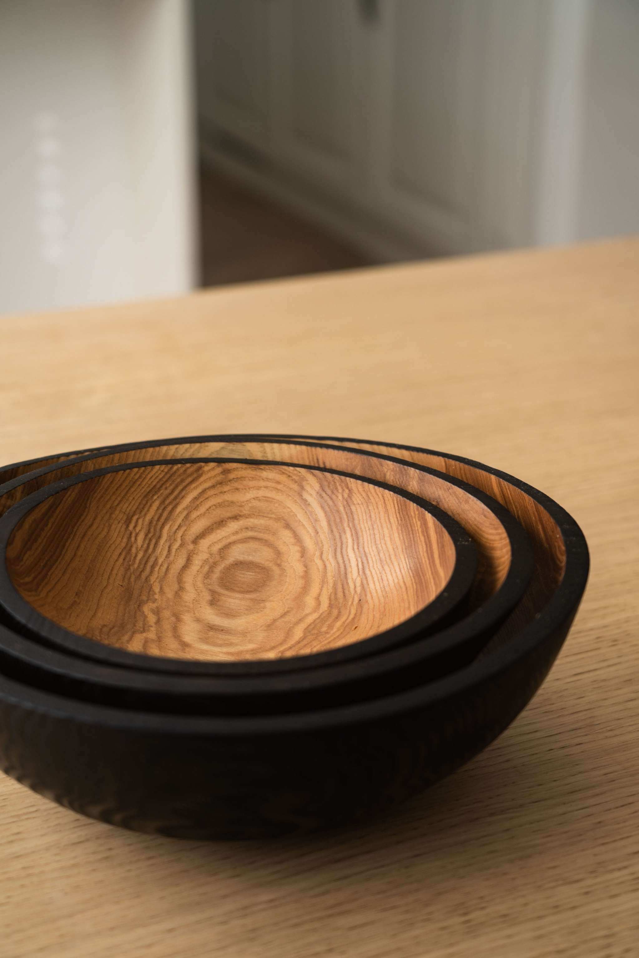 Half charred ashwood nesting bowl set showcasing three sizes, perfect for serving and displaying food.