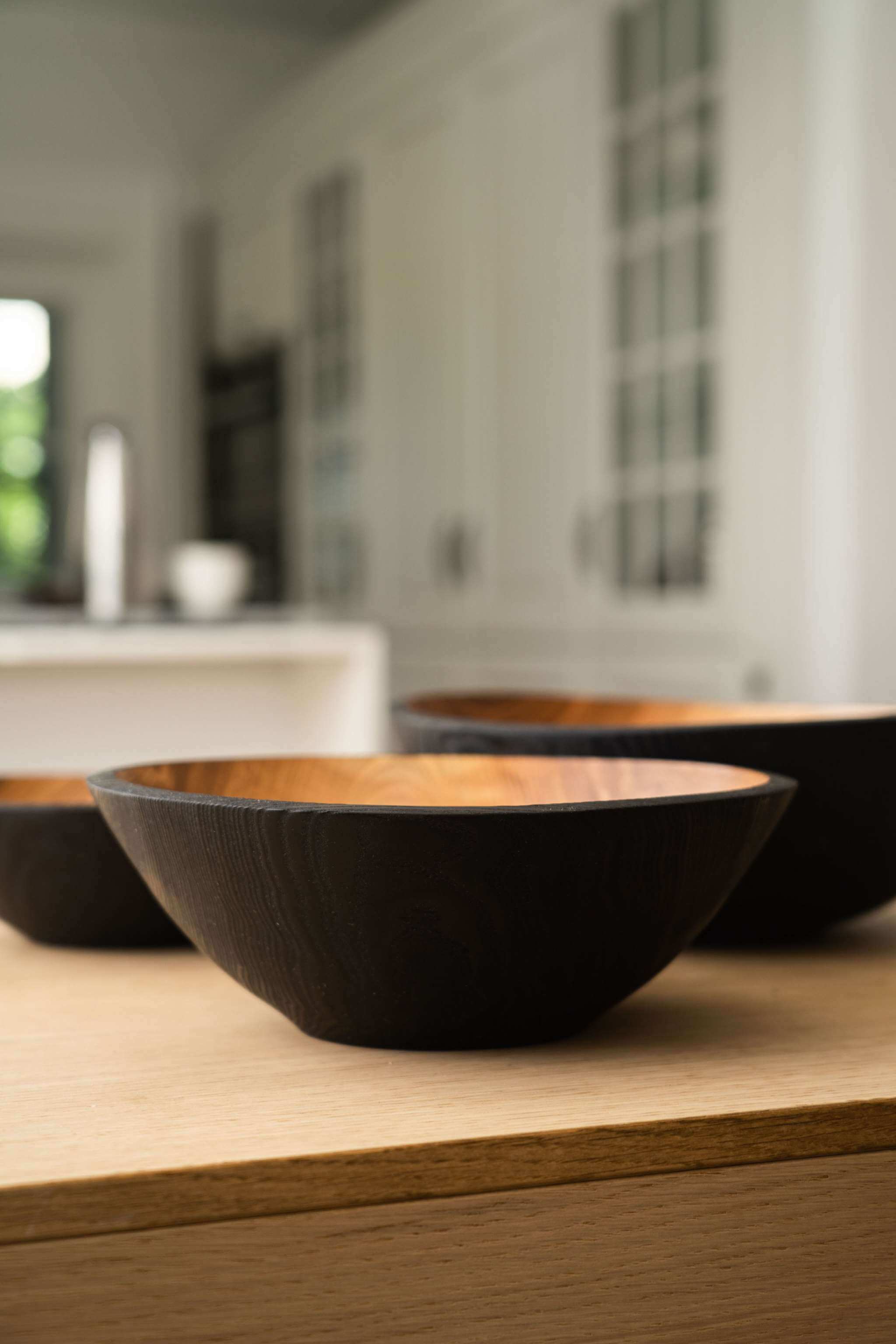 Half Charred Ashwood Nesting Bowl Set Half charred wood nesting bowl set displayed on a kitchen countertop, showcasing the unique texture and color.