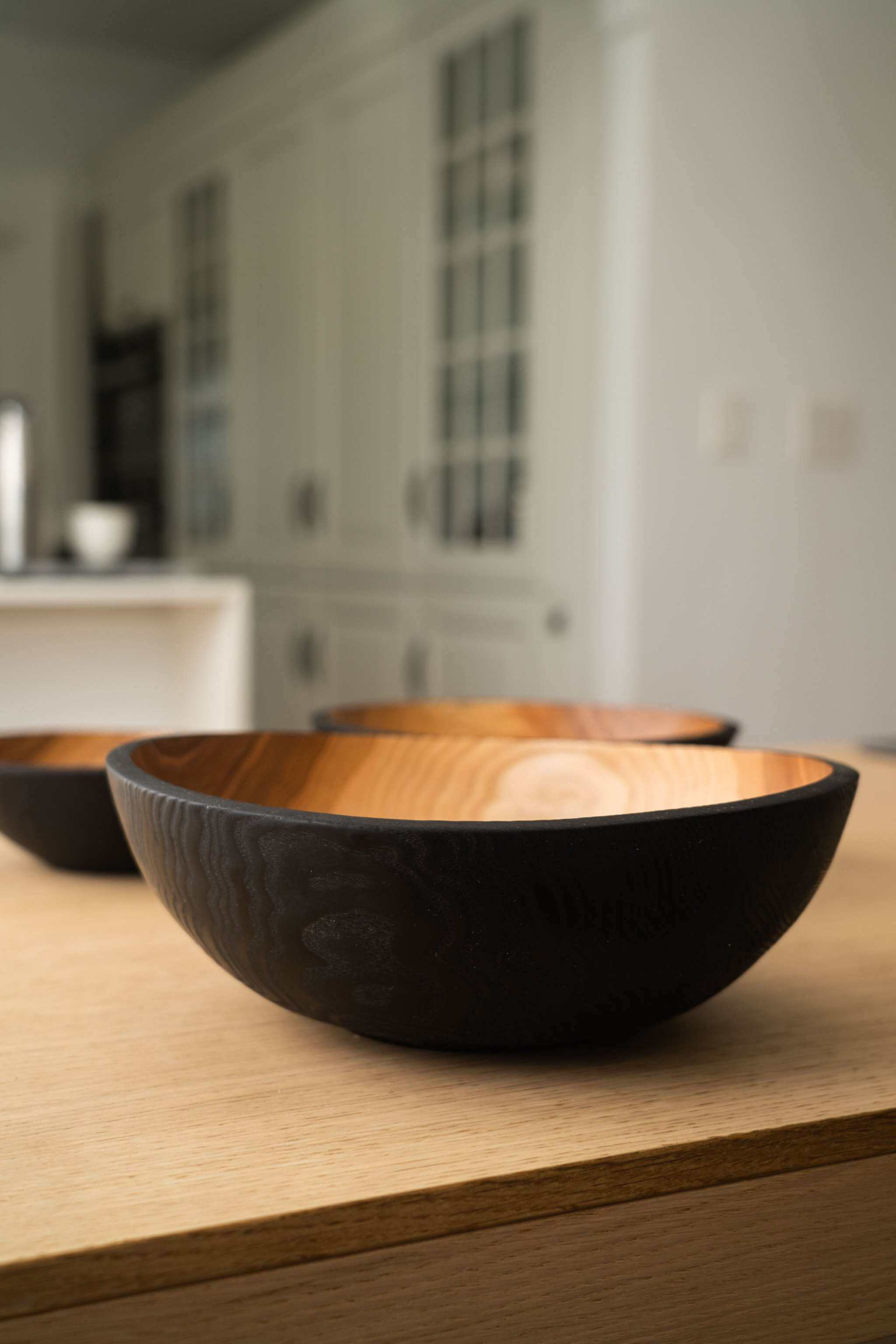 Half Charred Ashwood Nesting Bowl Set Half charred ashwood nesting bowl set on a wooden table, showcasing the elegant contrast between dark and light wood.