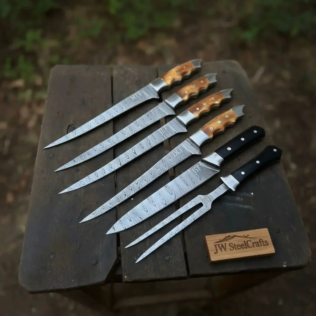 Handmade damascus boning knife set displayed on a wooden table, featuring black and orange resin handles.