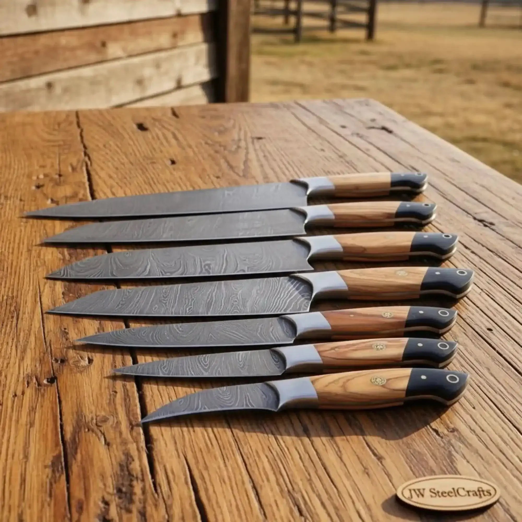 8-piece damascus fillet knife set with olive wood and black resin handles displayed on a wooden table.
