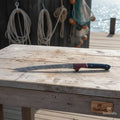 13-inch Damascus boning knife on a wooden table, showcasing the blue and red two-tone resin handle and detailed blade.