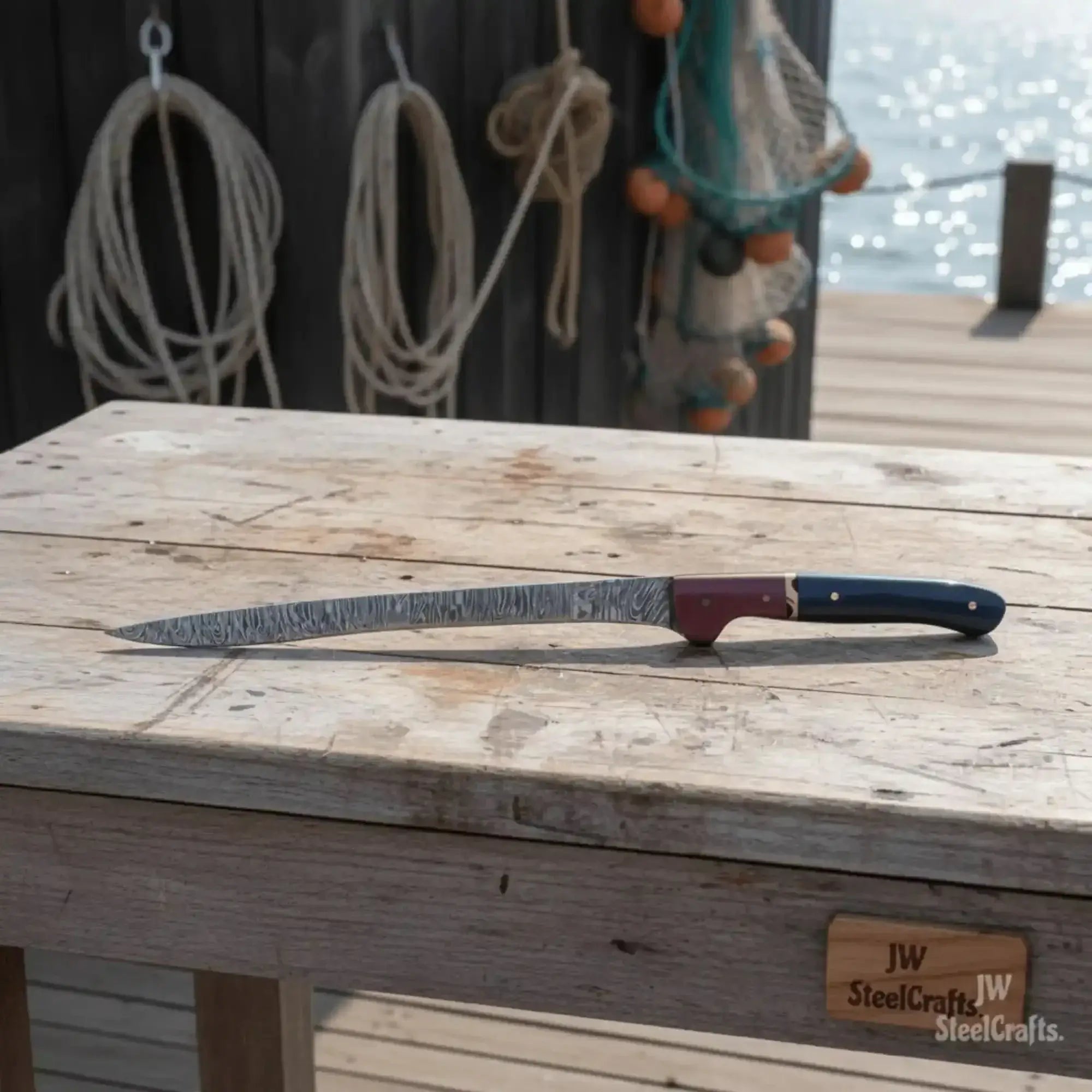 13-inch Damascus boning knife on a wooden table, showcasing the blue and red two-tone resin handle and detailed blade.